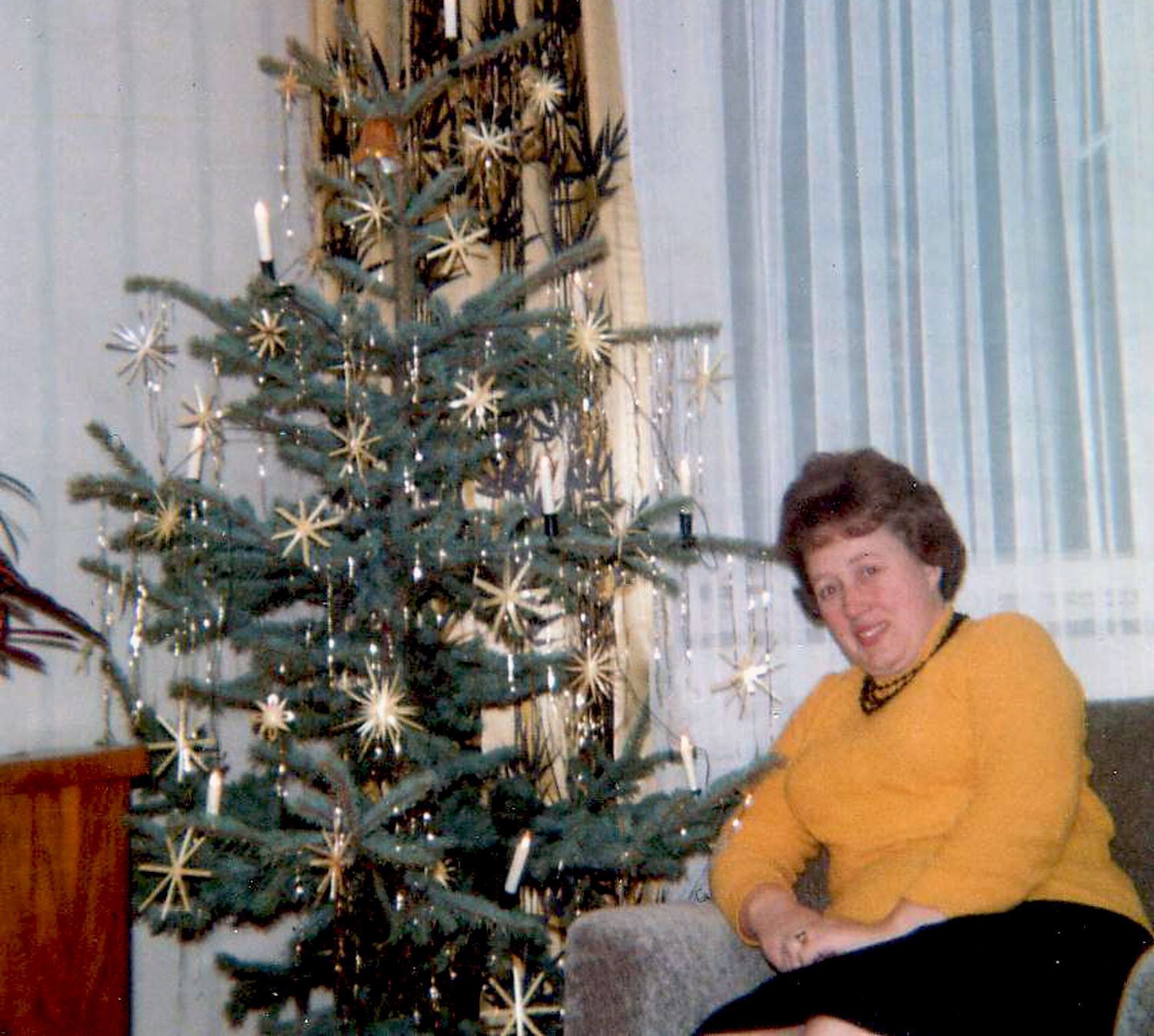 24. Dezember 1967: Eine Frau sitzt an Heiligabend neben einem geschmückten Christbaum.
