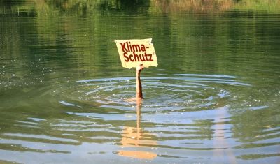 Tauchender Mensch hält Schild mit der Aufschrift "Klimaschutz" aus dem Wasser