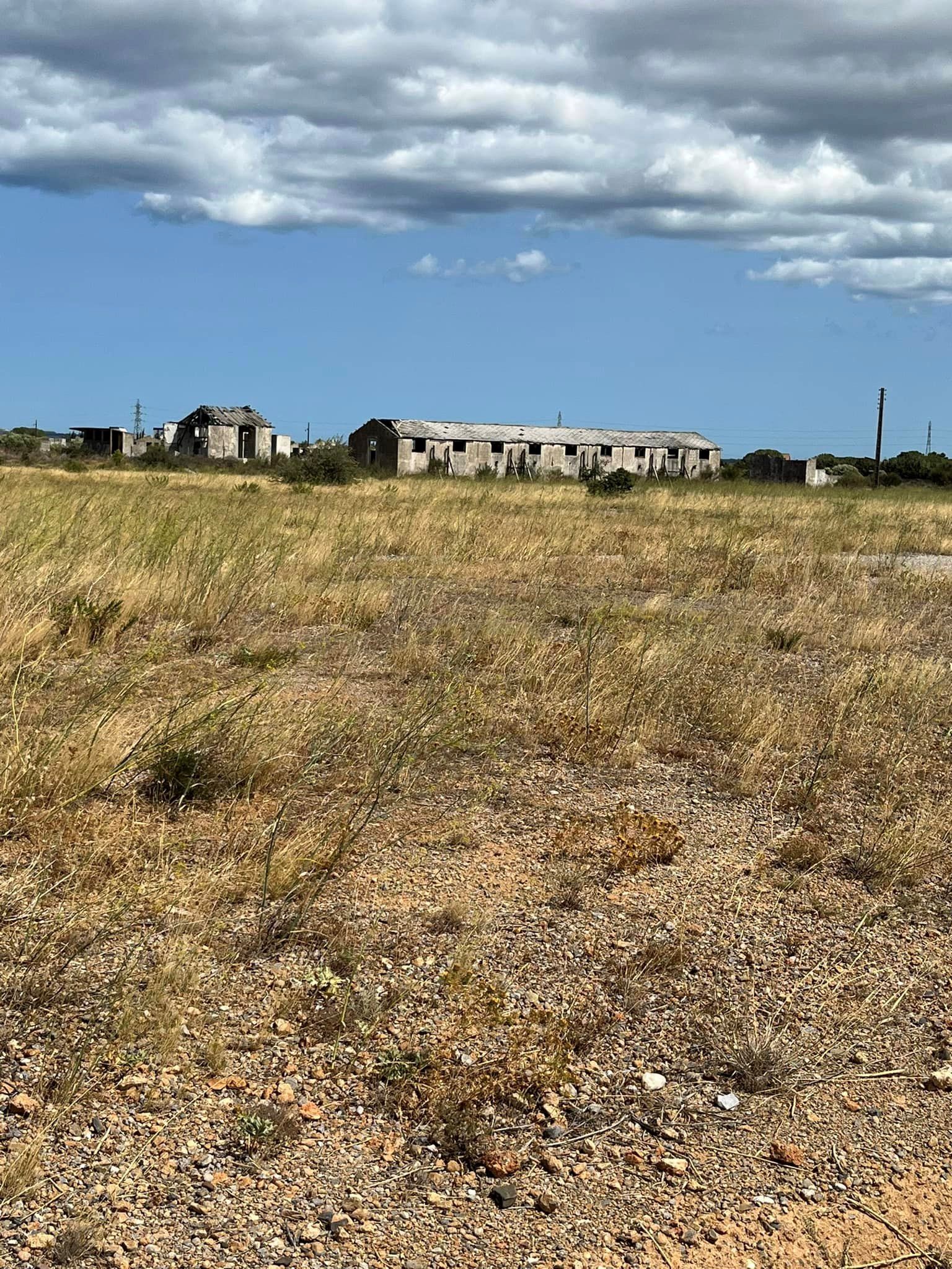 Verfallende Baracke am Ende eines weiten mit trockenem Gras bewachsenen Platzes