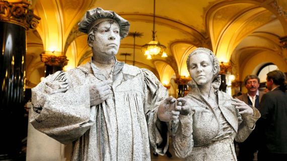 Tradition in Bewegung: Luther und Katharina von Bora, scheinbar in Stein gehauen, als Walking Act.