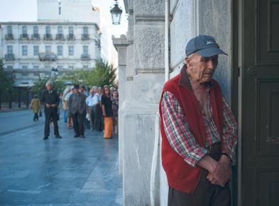 Ein griechischer Rentner in diesem Sommer in Athen. Im Hintergrund warten Menschen auf die Wiedereröffnung einer Bank. Foto: dpa/ Dimitris Michalaskis