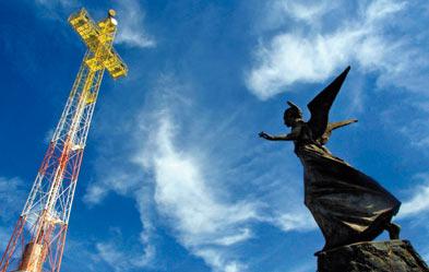 Vis-à-vis: Eine Heiligenstatue und der Sendemast von Radion Vatika in Kreuzform. Der Sender verschlingt große Summen. (Foto: dpa/Alessandro Bianchi)
