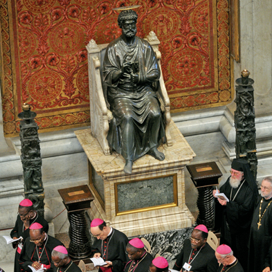 Bischöfe beten unter der Bronzestatue des Apostels Petrus im Petersdom, deren rechter Fuß von den Berührungen der Besucher blank gescheuert ist. Foto: dpa/ABACAPRESS.com